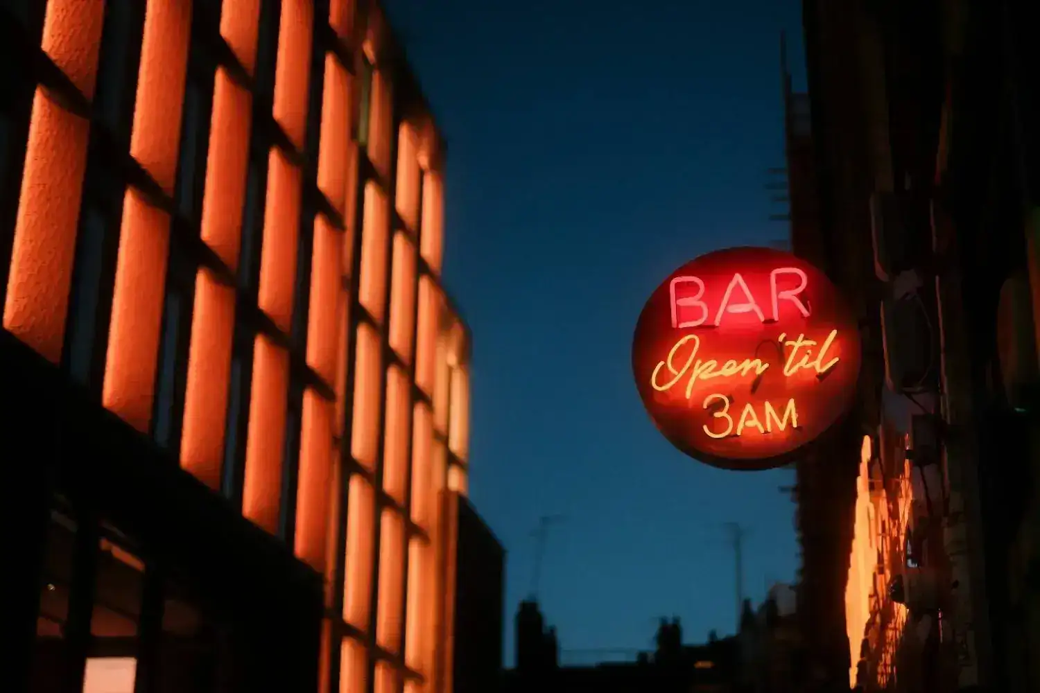 A glowing red circular neon bar sign at night.