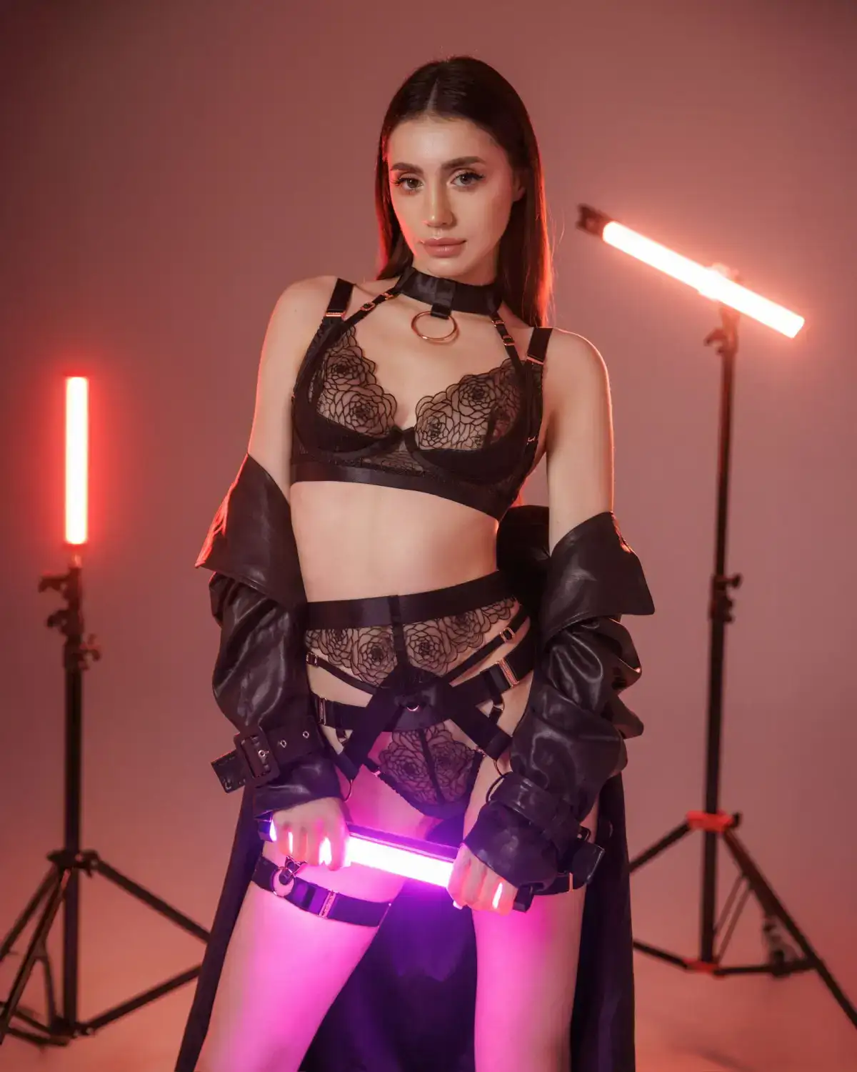 Woman in black lace lingerie holding a pink light tube.