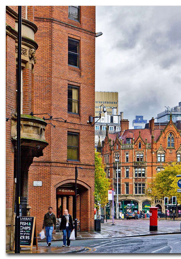 Autumnal street scene in Manchester with red brick buildings.